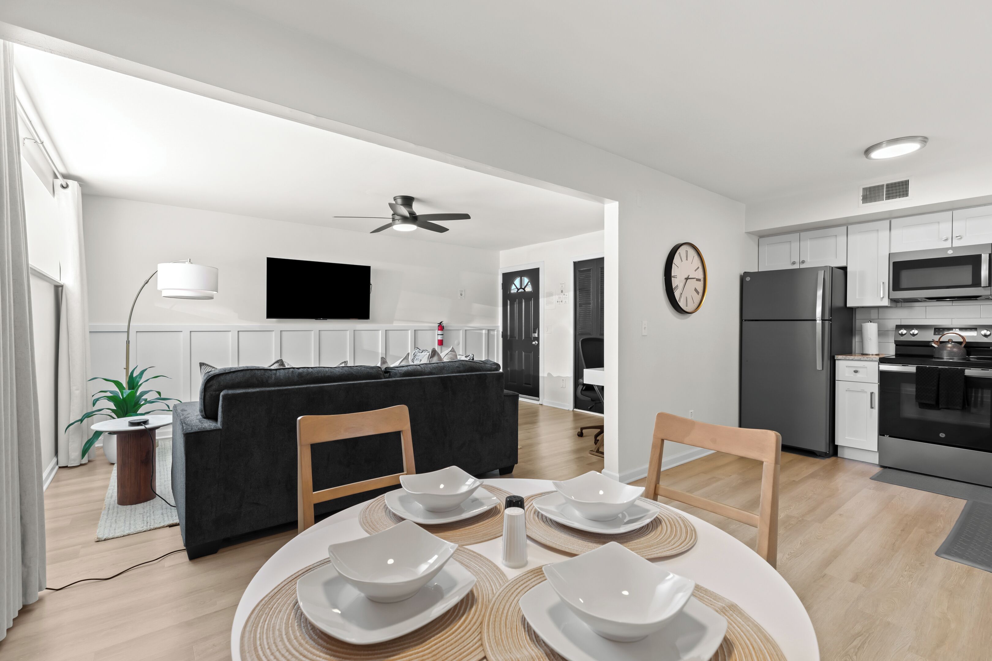 Eine moderne Küche mit weißen Schränken, einer eingebauten Mikrowelle und einem Edelstahl-Kühlschrank.