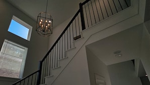 A staircase with a black railing, a chandelier, and a door at the bottom. - Spacious 5-bedroom house with WiFi, AC in brilliant Mesquite (Mesquite)