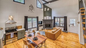 A spacious living area with a fireplace, wooden flooring, and a dining table set for four. - Welcome to Tangled Up Cabin! A Luxury Adults Only HotTub/Sauna Playroom (Blue Ridge)