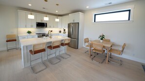 Een moderne keuken met witte kasten, roestvrijstalen apparatuur en een centraal eiland met barstoelen.