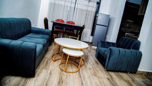 Um espaço compacto com sofá, mesa de jantar e cadeiras, e uma geladeira.