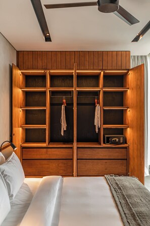 A bedroom with a large wooden wardrobe, a bed with white linens, and a ceiling fan. - Body Factory Lifestyle Residence Canggu (Canggu)