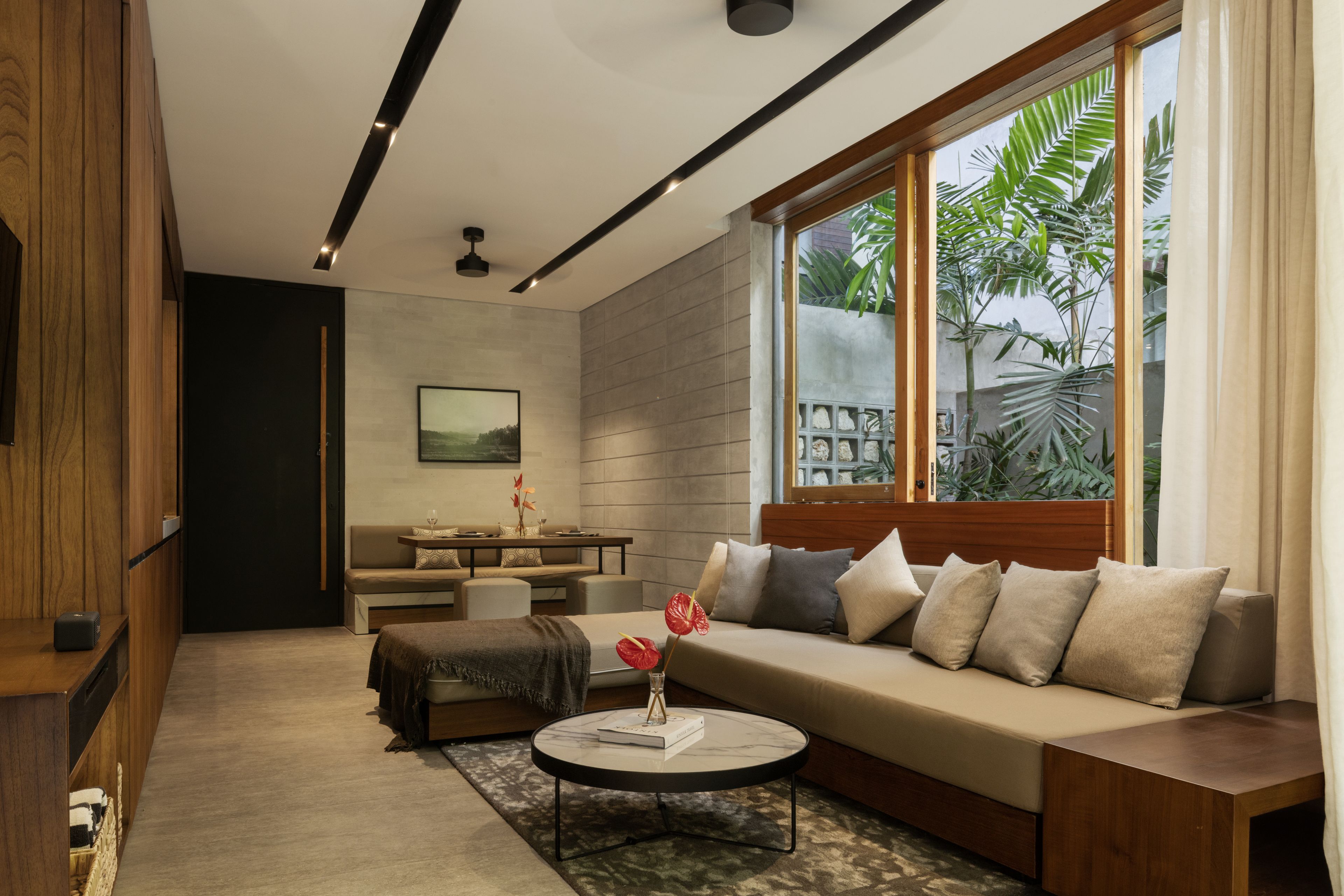 A modern living room with a sofa, coffee table, and a dining area.