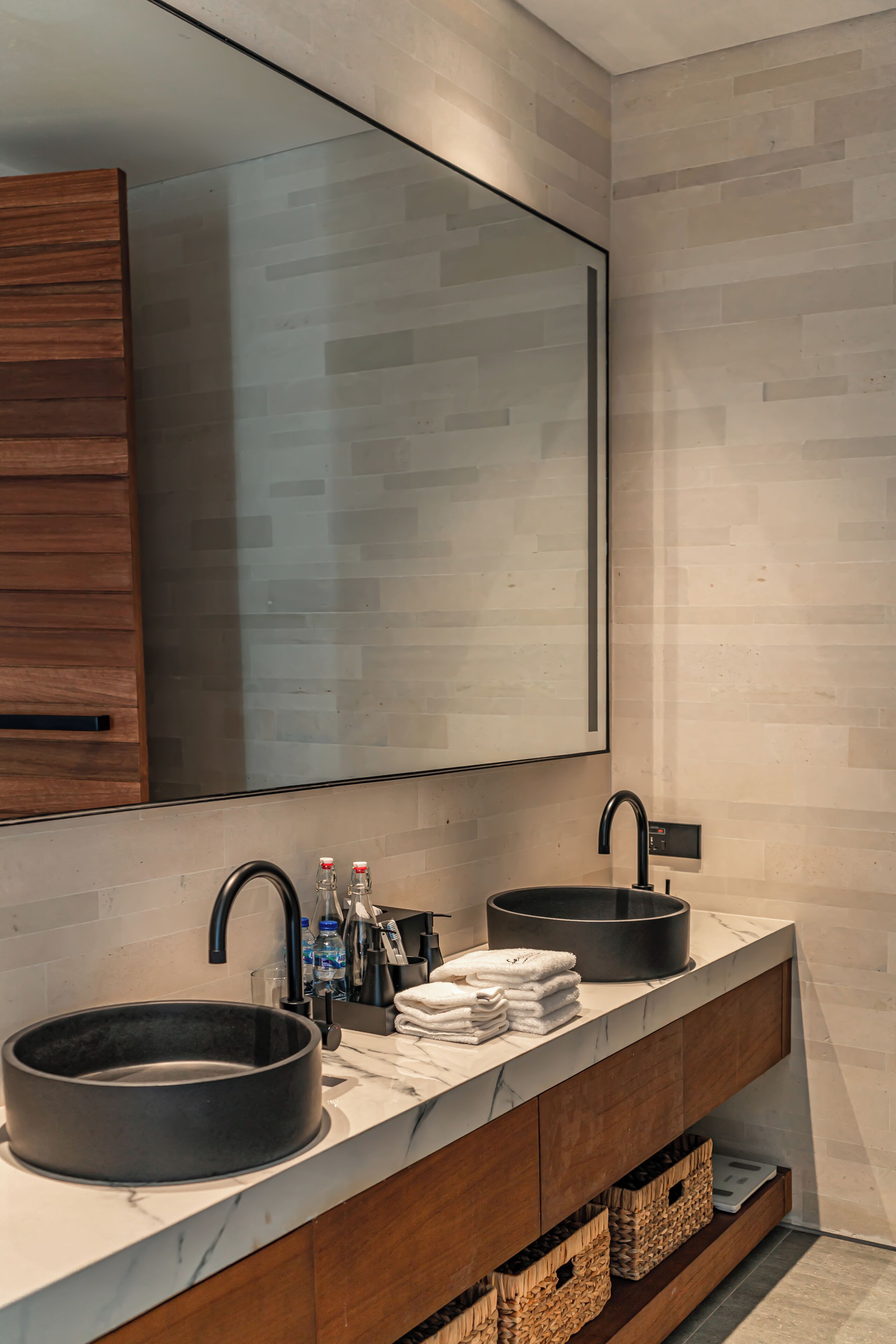 Un baño moderno con dos lavamanos, un espejo grande y armarios de madera.