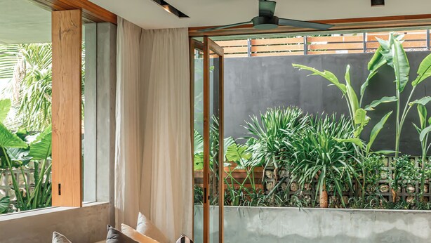 Ein modernes Wohnzimmer mit einer Couch, einem Couchtisch und großen Fenstern mit Blick auf einen Garten.