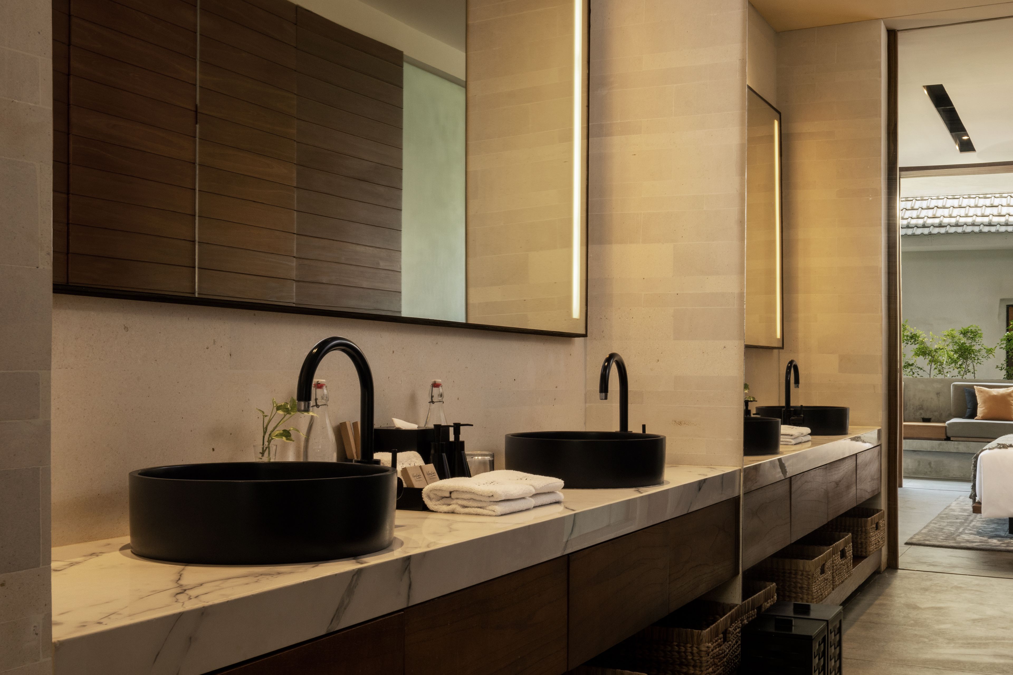 Une salle de bain moderne avec deux lavabos noirs, un grand miroir et un meuble-lavabo en bois.
