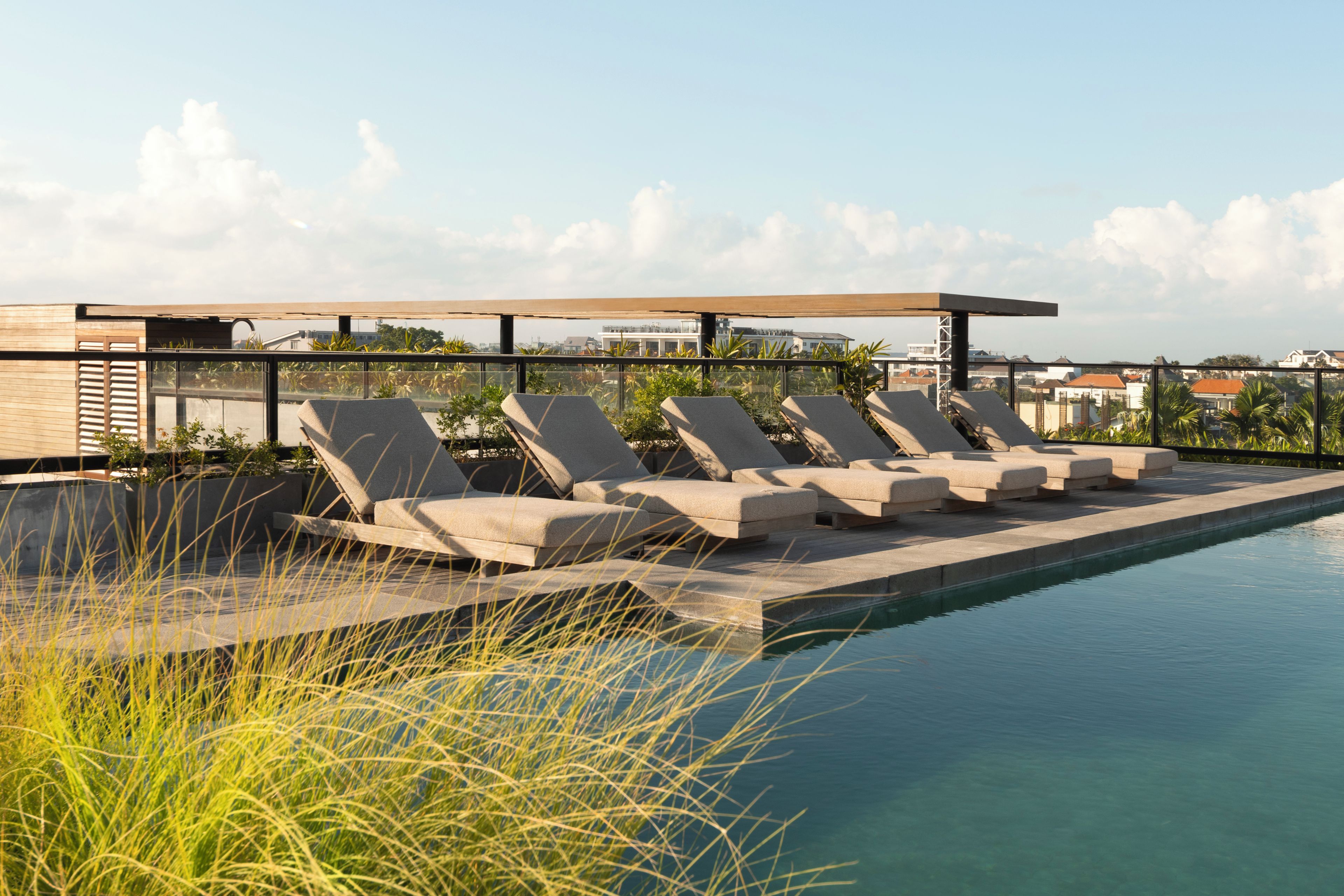 A rooftop pool area with lounge chairs and a view of the cityscape.
