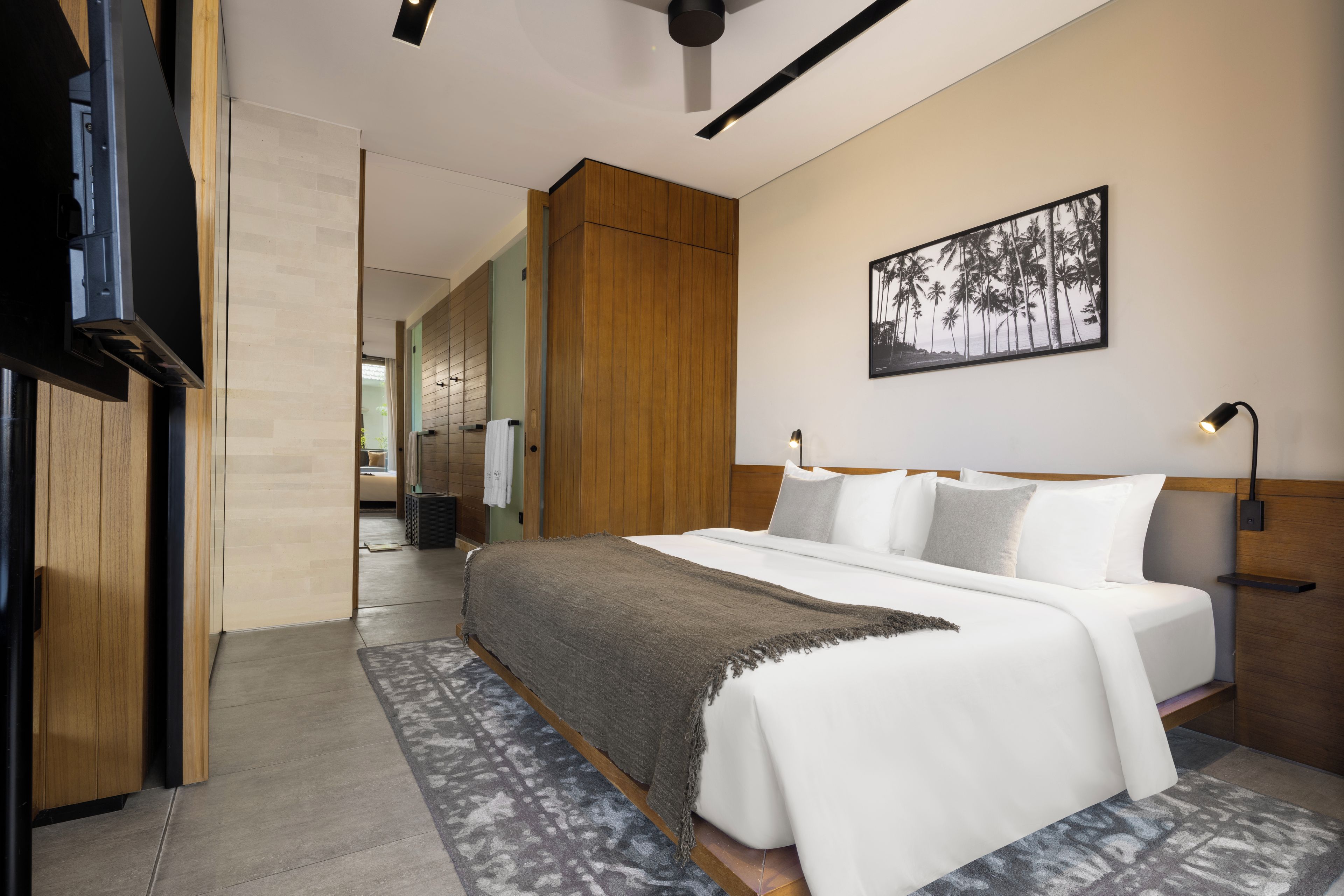 A modern hotel room with a large bed, a flat-screen TV, and a framed picture on the wall.