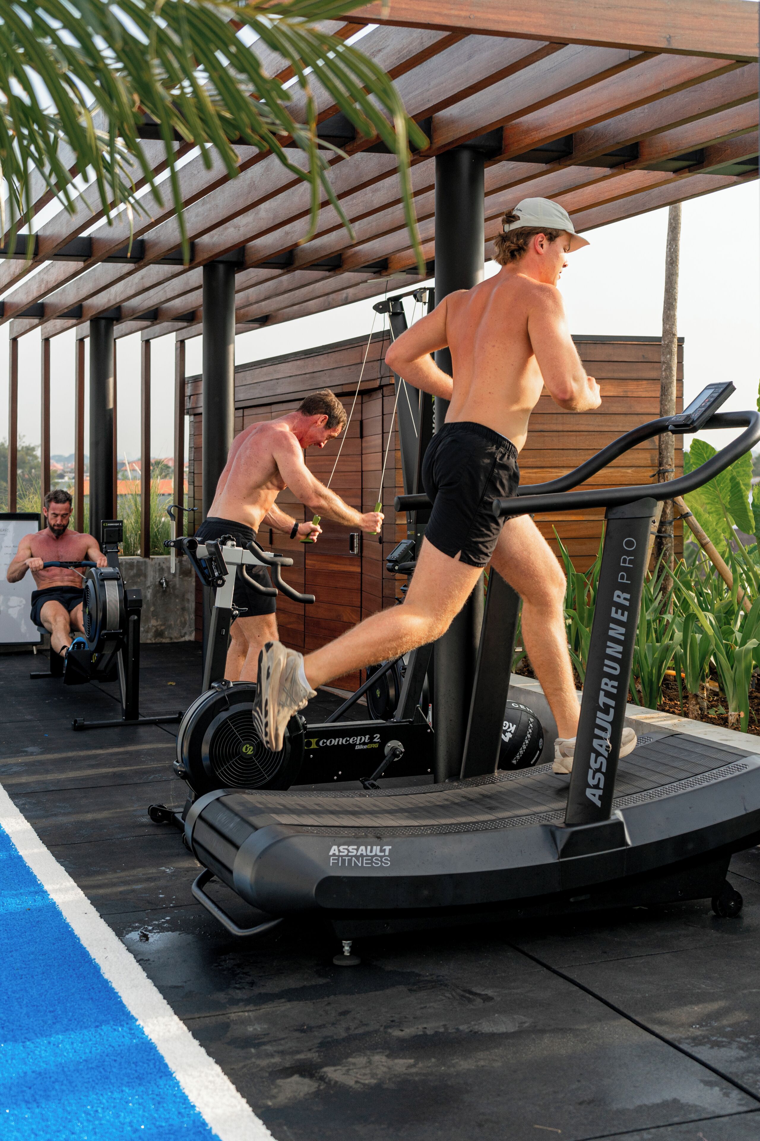 A fitness area with treadmills and stationary bikes, a covered roof, and a poolside setting.
