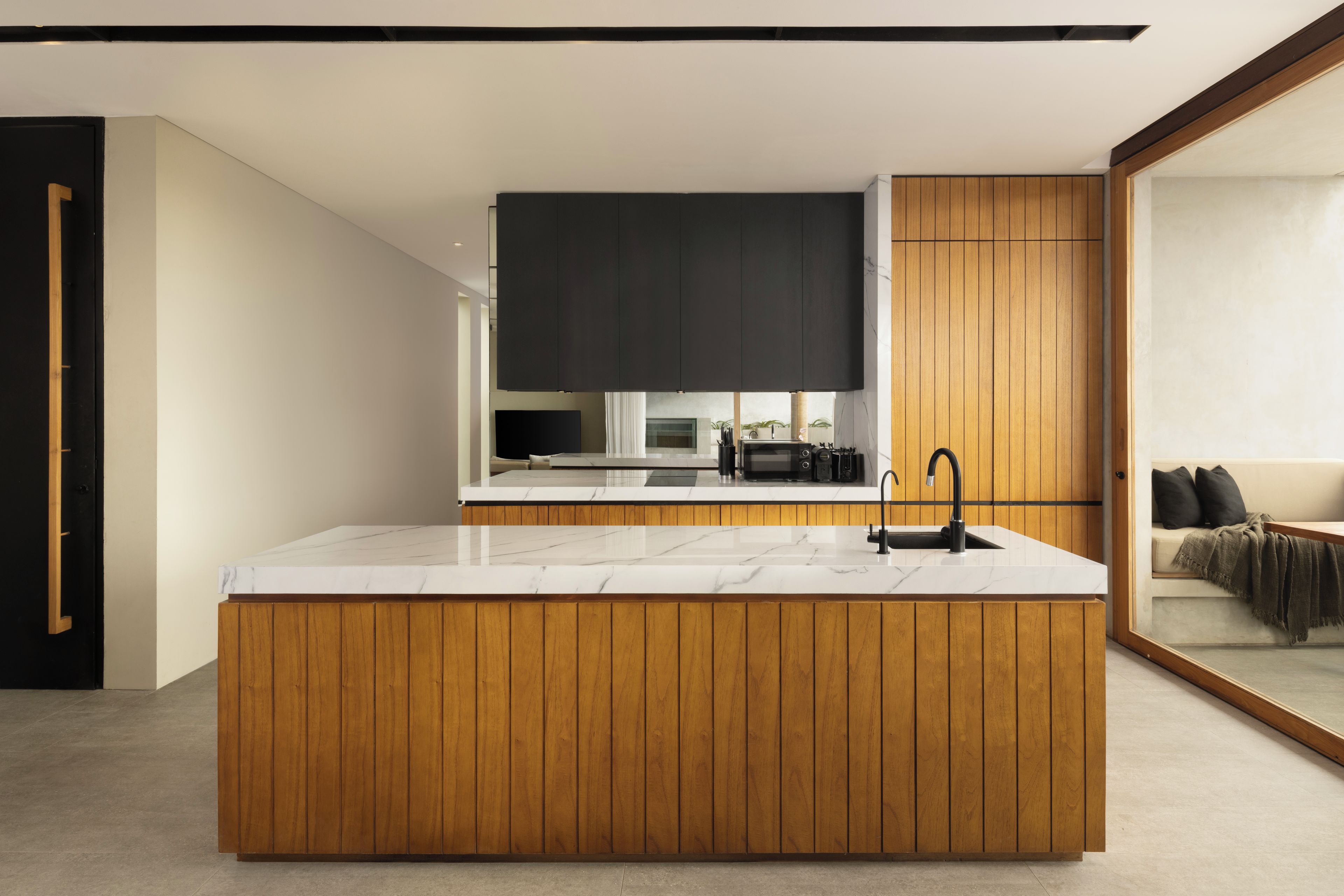 Una cocina moderna con encimera de mármol, paneles de madera y un grifo negro.