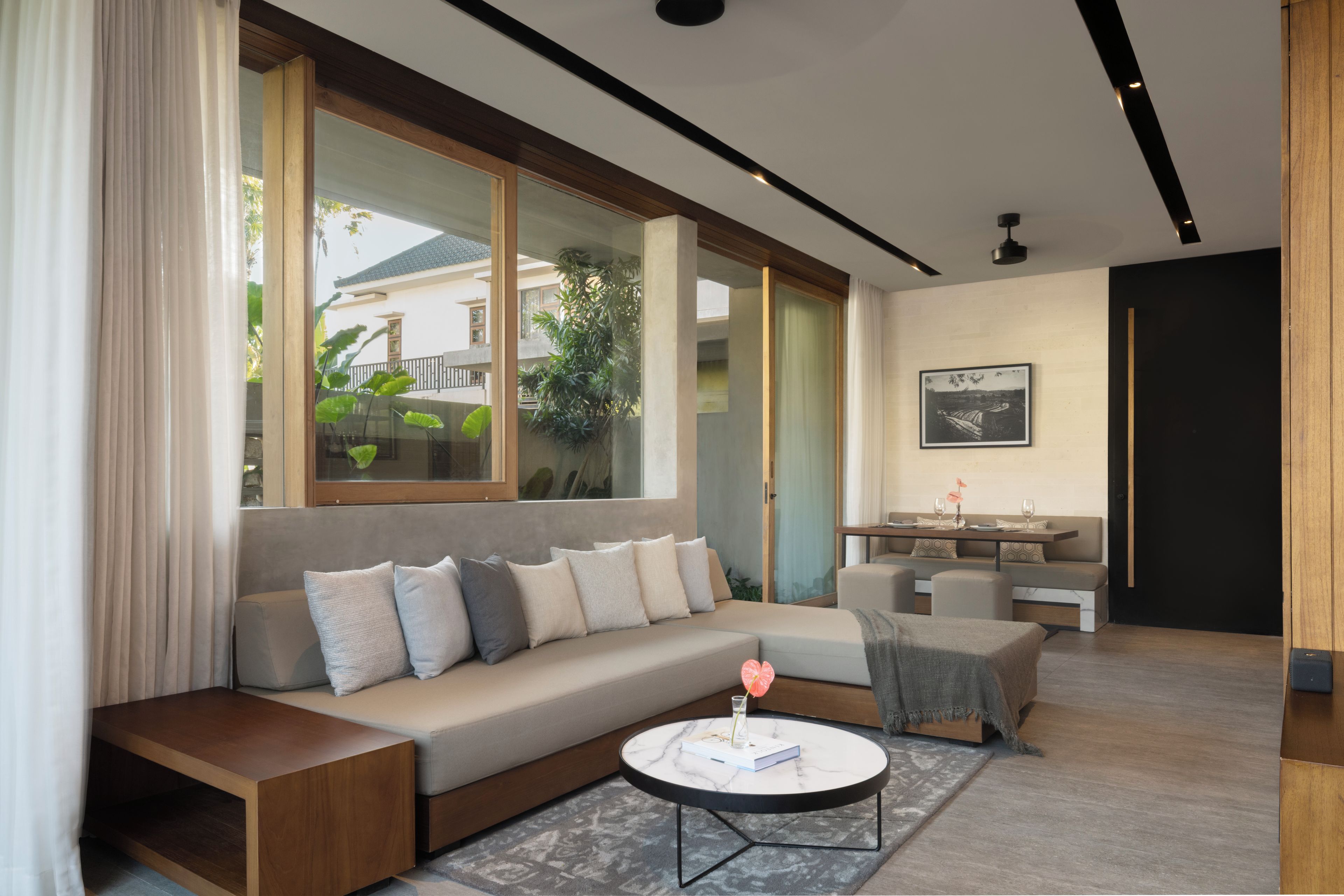 A modern living room with a sofa, a coffee table, and a dining area.
