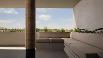 A modern outdoor seating area with a sofa and a tall, textured column.