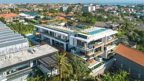 A modern multi-story building with a rooftop pool, surrounded by residential areas and a clear view of the sea. - Body Factory Lifestyle Residence Canggu (Canggu)