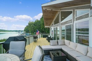 Um deck com móveis de exterior, vista para o lago e uma bandeira americana.