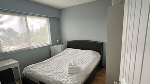 Et soveværelse med seng, natbord og et vindue.