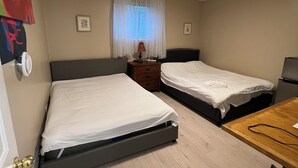 Et soveværelse med to enkeltsenge, et træskrivebord, en stol og et lille bord med en lampe.