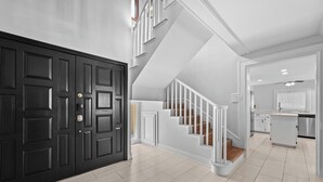 Un interior moderno con una escalera, una zona de cocina y una puerta negra.
