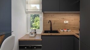 Una cocina moderna con encimera de madera, pileta negra y una ventana con persianas.