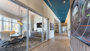 A modern office space with a glass partition, a conference table, and a kitchen area visible through the partition. - Daytona 2BR Getaway Parking Family & Pet-friendly (Daytona Beach)