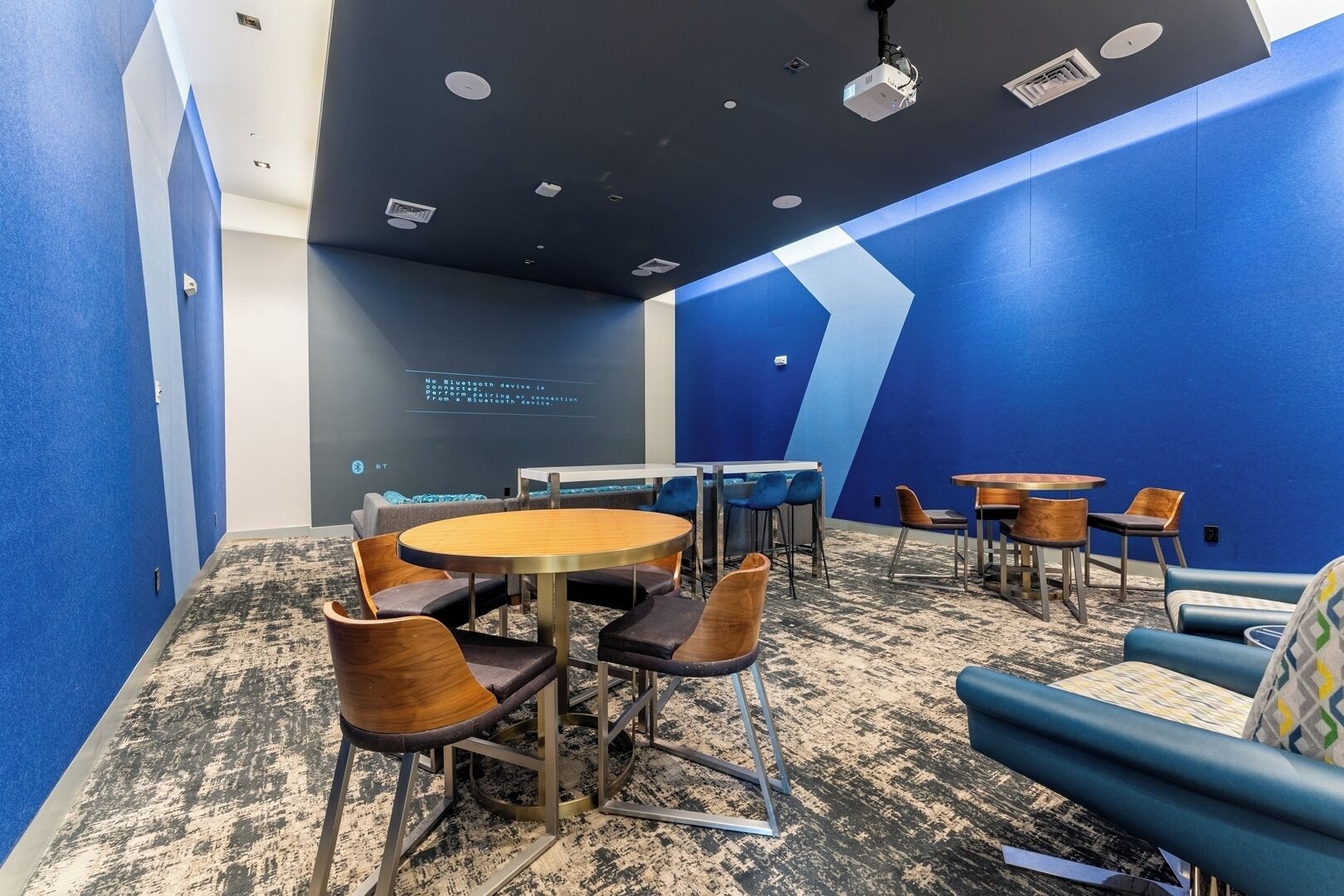 Un salón de conferencias con una mesa redonda, sillas y una pared azul decorativa.