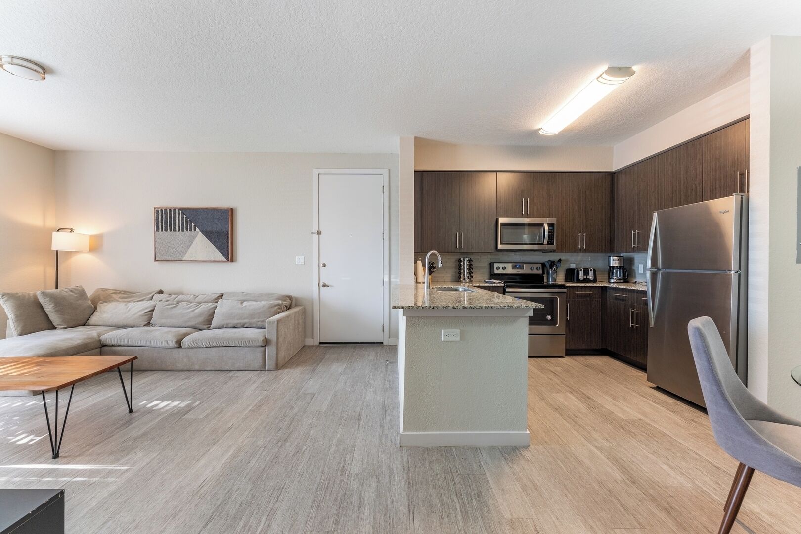 A modern apartment with a living room, kitchenette, and a small dining area.