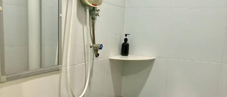 Un baño con un lavamanos blanco, un inodoro y una ducha con cabezal de ducha manual.