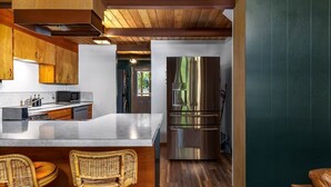 A modern kitchen with a central island, stainless steel appliances, and wooden cabinetry. - Charming, rustic cabin on the golf course (Packwood)