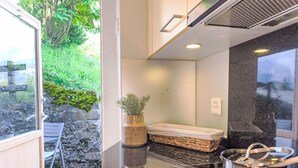A modern kitchen with a built-in stove, a small sink, and a window overlooking greenery. - Galliweidli by Interhome (Wengen)