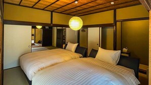 A hotel room with a wooden ceiling, two beds with white bedding, a hanging lamp, and a mirror on the wall.