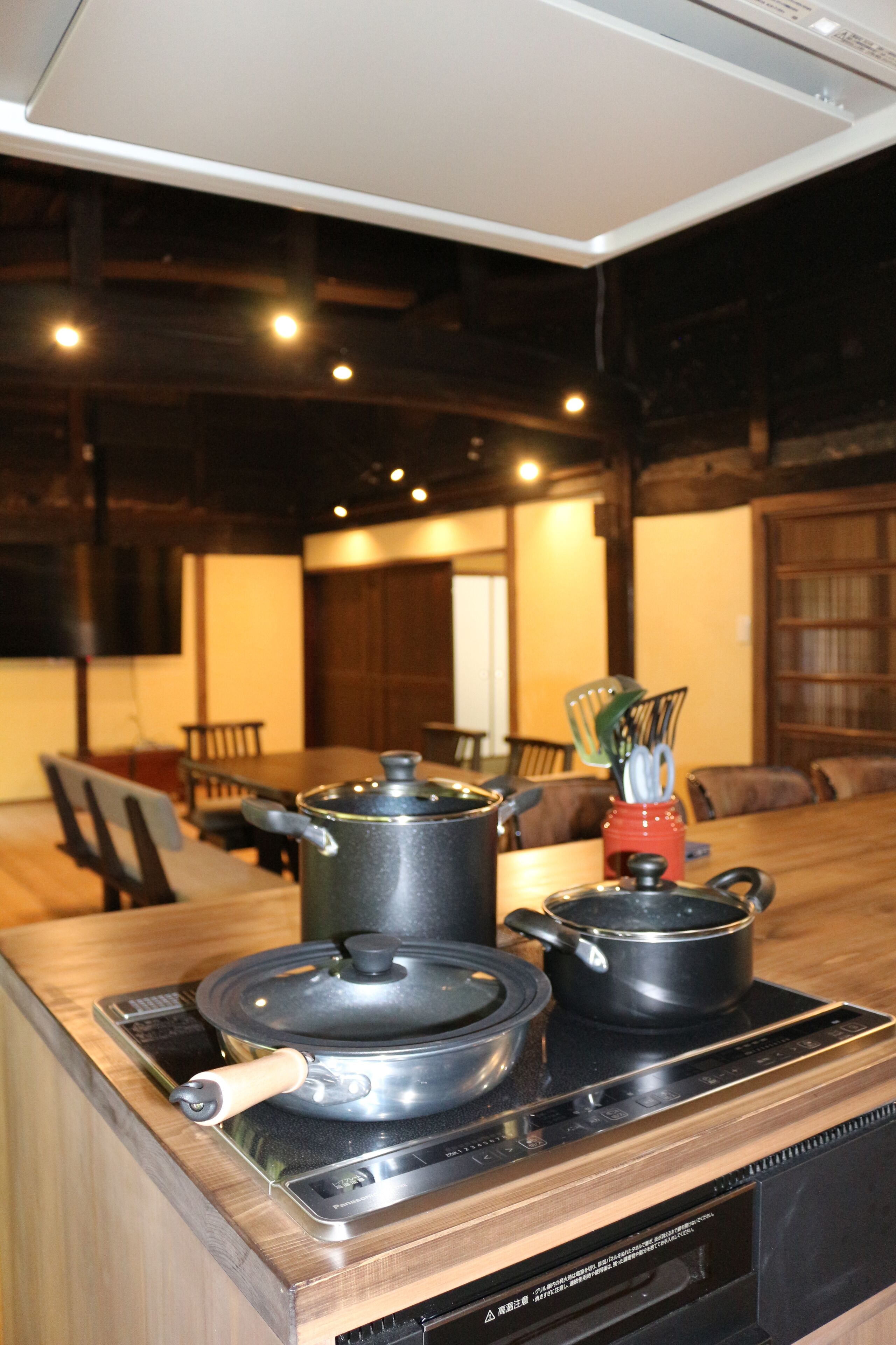 A kitchen with a stove, pots, and a dining area with chairs and a table.