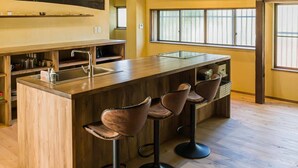 A spacious kitchen with a large island, wooden bar stools, and a high ceiling with exposed beams.