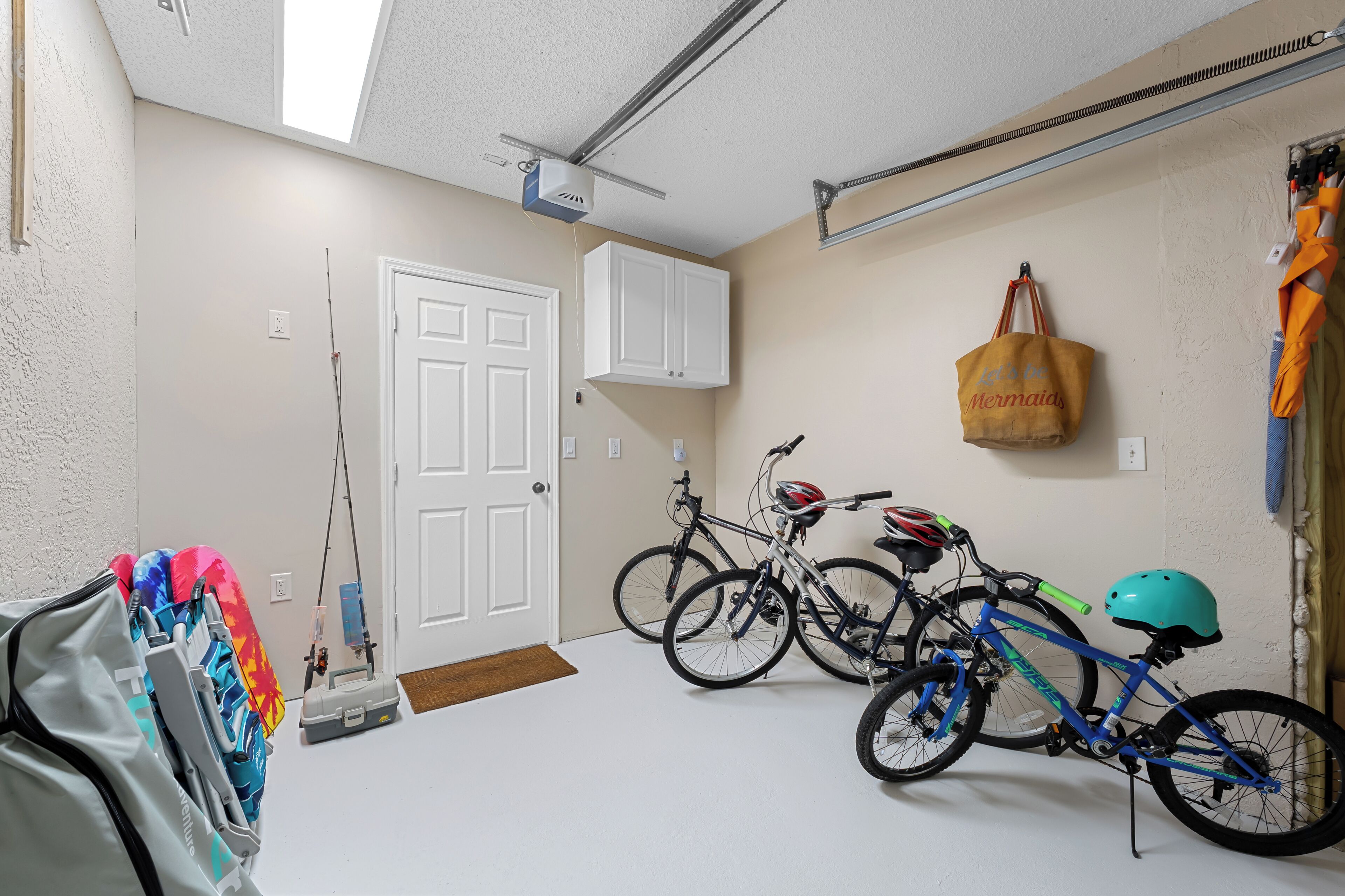 A garage with two bicycles, a white door, and a ceiling light.
