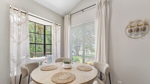 Un comedor con una mesa redonda, cuatro sillas, una planta en maceta y una lámpara fijada a la pared.