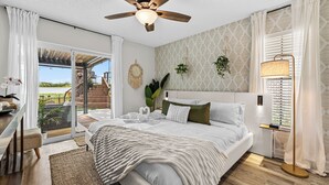 Un dormitorio moderno con una cama grande, un ventilador de techo, una mesita de noche y vistas al exterior.