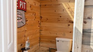 A small wooden bathroom with a skylight, a toilet, and a sign on the wall.