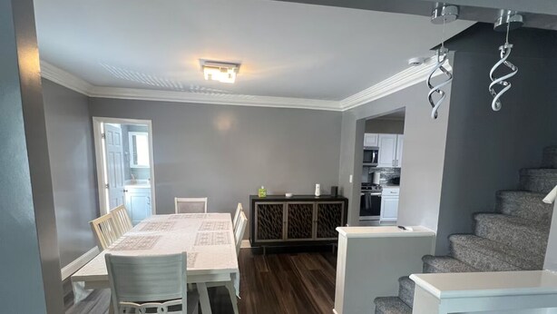 A modern living room with a dining area, a staircase, and a kitchen in the background. - Spacious 4-bedroom fully remodeled home in charming Sandusky (Sandusky)
