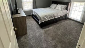 A bedroom with a bed, a desk, and two windows. - Spacious 4-bedroom fully remodeled home in charming Sandusky (Sandusky)
