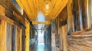 A wooden hallway with a tiled floor, a hanging light fixture, and a view into another room. - The Link Farmstay (Sa Pa)