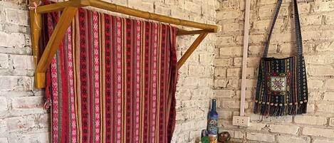 A room with a brick wall, a wooden bench, a fan, and a hanging bag.