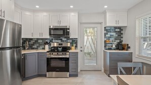 A modern kitchen with stainless steel appliances, grey cabinets, and a tiled backsplash.
