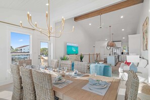 Uma sala de jantar moderna com cadeiras de vime, uma mesa de madeira posta para refeição e um candelabro.