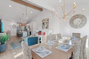 Un vaste espace dédié à la salle à manger, avec une longue table dressée pour le repas, entourée de chaises en osier.