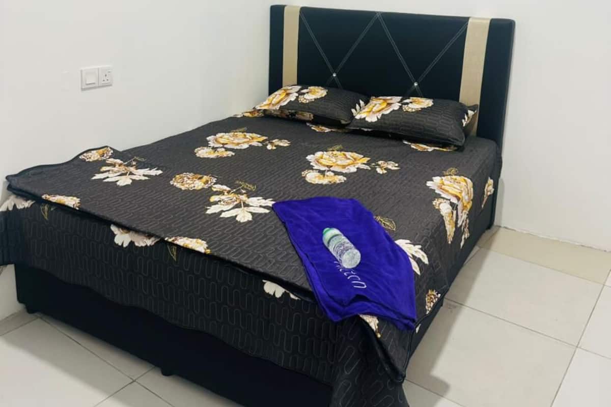 A bed with a floral bedspread, a headboard with diagonal lines, and a blue towel on the footboard.