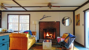 A living room with a fireplace, a sofa, a chair, and a dresser.