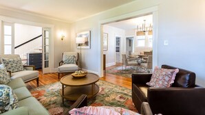 A spacious living room with a round coffee table, two sofas, a chair, and a dining area in the background.