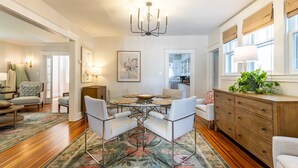 A spacious dining area with a round table, four chairs, and a chandelier.