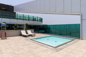 A rooftop pool with two lounge chairs, a fire extinguisher, and a glass railing. - Urban Parkside Living Near the Iconic Dubai Frame (Dubai)