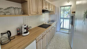 A kitchen with wooden cabinets, a black countertop, and a window with a view of greenery. - Swimming pool, Wi-Fi, private garage, terrace, walking distance to beaches and shops. (ST MANDRIER SUR MER)