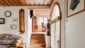 A cozy living room with a wooden sofa, a staircase leading to a loft area, and a large window with a view. - Kvarnfallet 40 by Interhome (Källsjö)