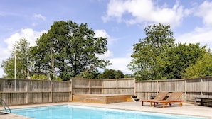 A wooden deck with a swimming pool, wooden lounge chairs, and a wooden fence. - Kvarnfallet 40 by Interhome (Källsjö)